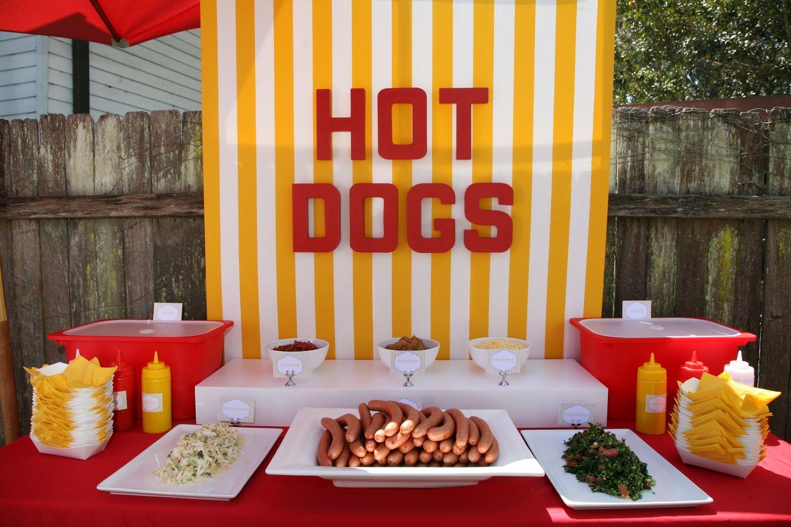 A table of hot dogs and condiments with a sign that proclaims "Hot Dogs" in bold letters.